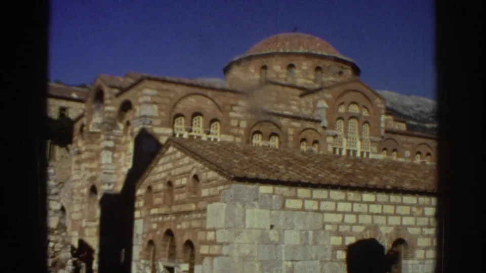 Central dome and windowed drum of a Byzantine church in Greece, 1976; snow-capped hills in the background; visitor shadow enters frame from lower left