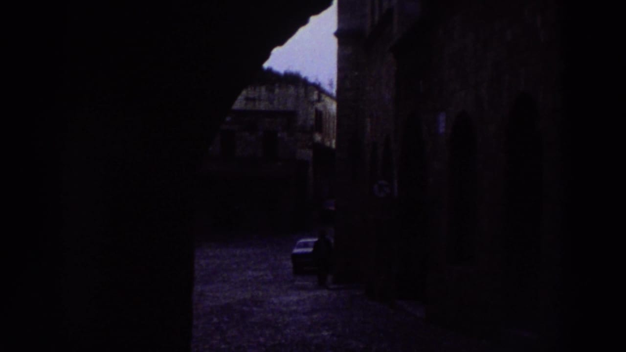 Dark stone archway passage in a Greek old town, likely captured mid-walk during a 1976 travel visit; heavily underexposed.