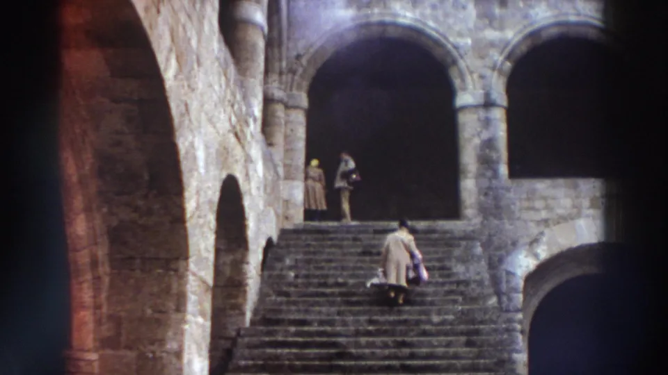 Wide stone staircase with multiple arches and two figures in dark robes at a historic Greek stone building, circa 1976.