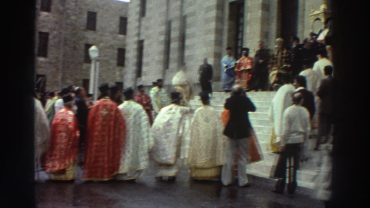 Greek Orthodox clergy in red and white vestments ascending wide stone steps toward a large stone church, Greece, circa 1976.