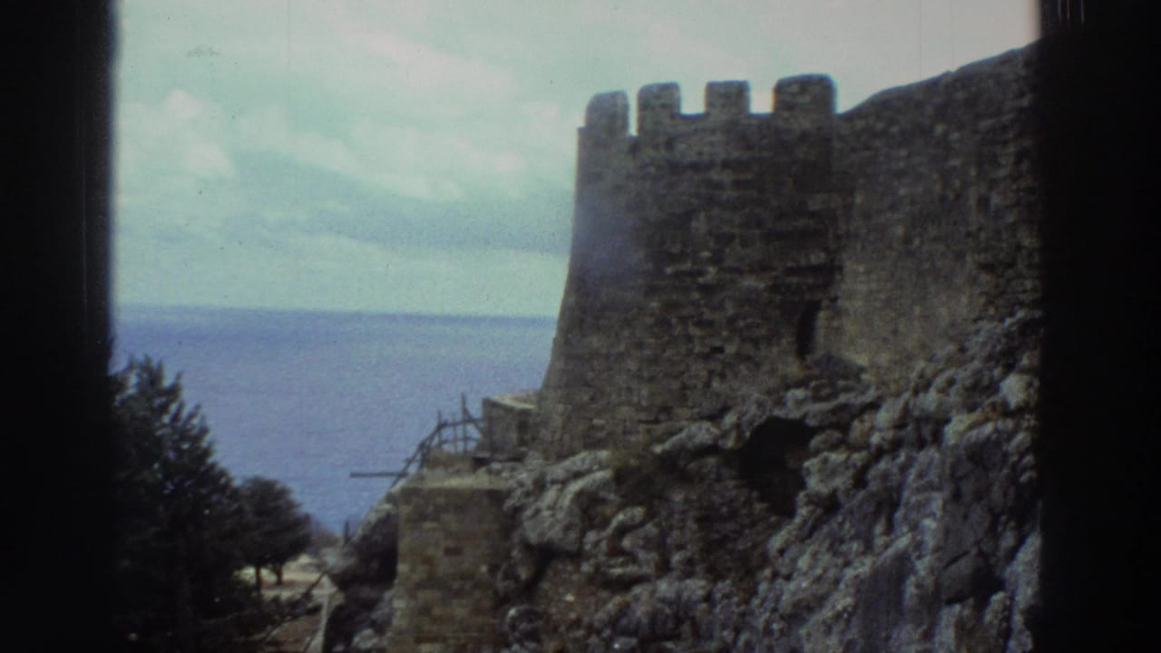 Stone castle wall on rocky ground overlooking the sea under a cloudy sky.