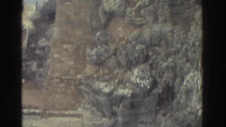 1976 Greece home-movie frame showing weathered stone ruins and a narrow walkway, with no clear people visible in this crop.