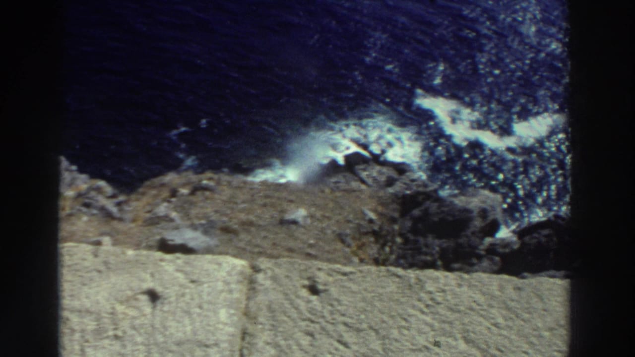 Coastal rocks and dark sea with waves splashing against the shoreline.