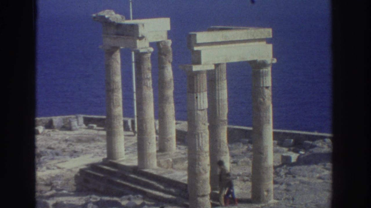 Weathered stone columns and block lintels stand near a deep blue sea with a small figure below.