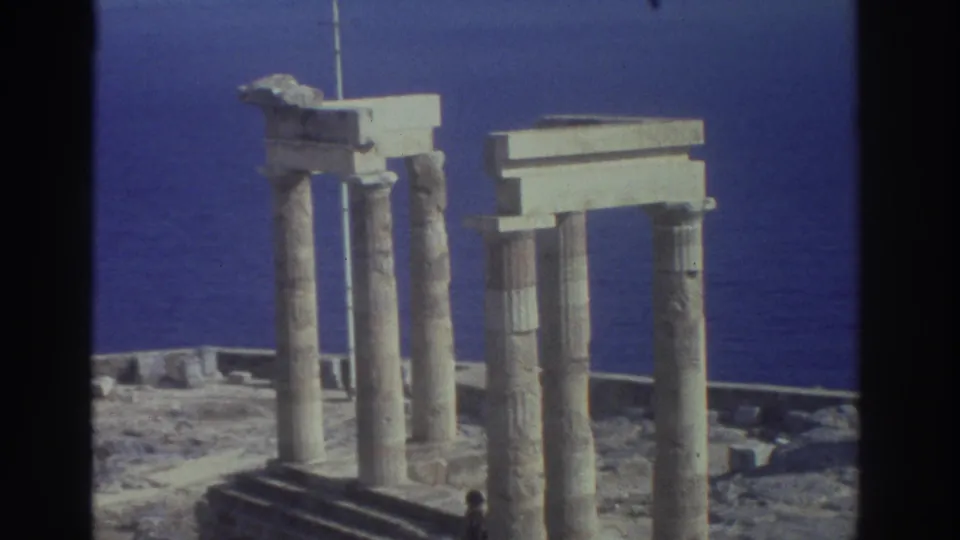 1976 Greece 8mm view of ancient seaside columns and rectangular stone lintels against the blue sea.