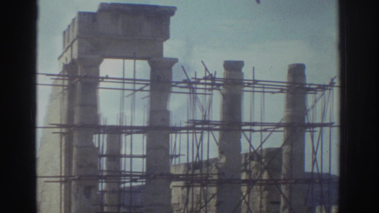 Stone ruins with scaffolding around columns under a faded sky.