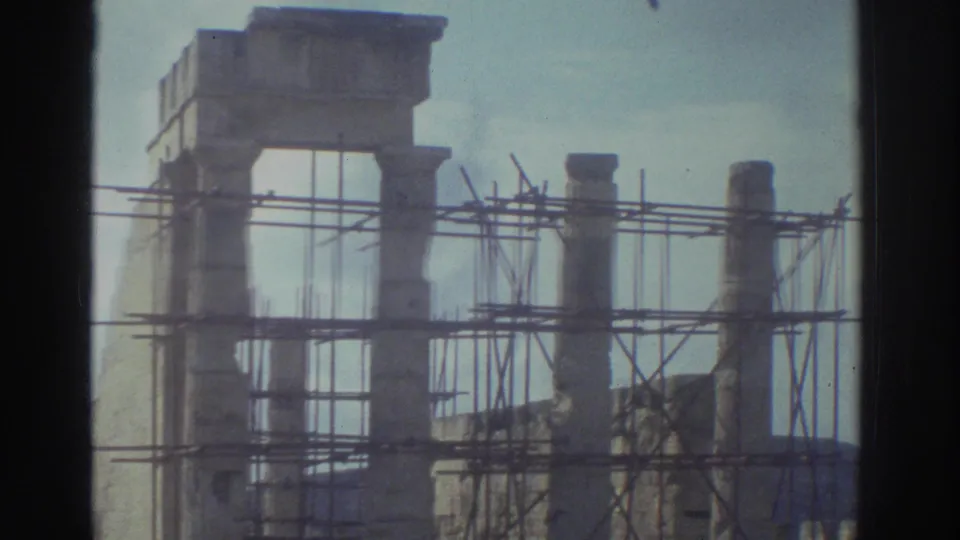 1976 Greece home-movie frame showing ancient stone ruins with scaffolding around columns, likely during restoration work.