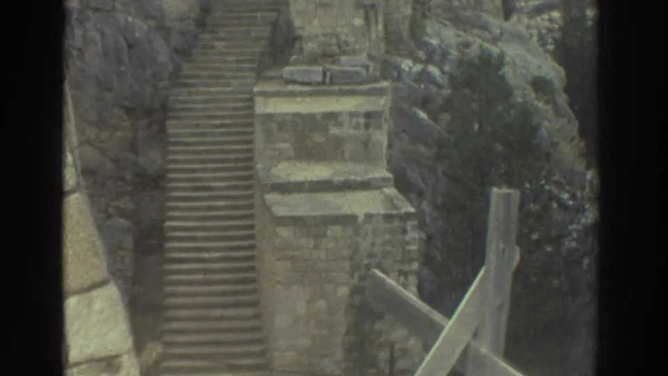 1976 Greece 8mm view of stone steps and masonry set into a rocky coastal cliff, with no people visible.
