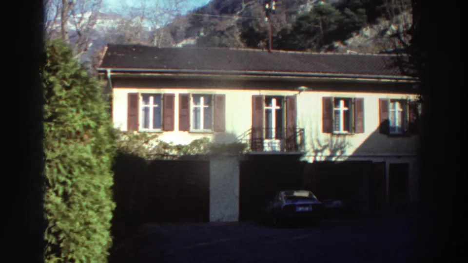 Residential building with shuttered windows and a parked car, consistent with a 1976 Greece home-movie exterior.