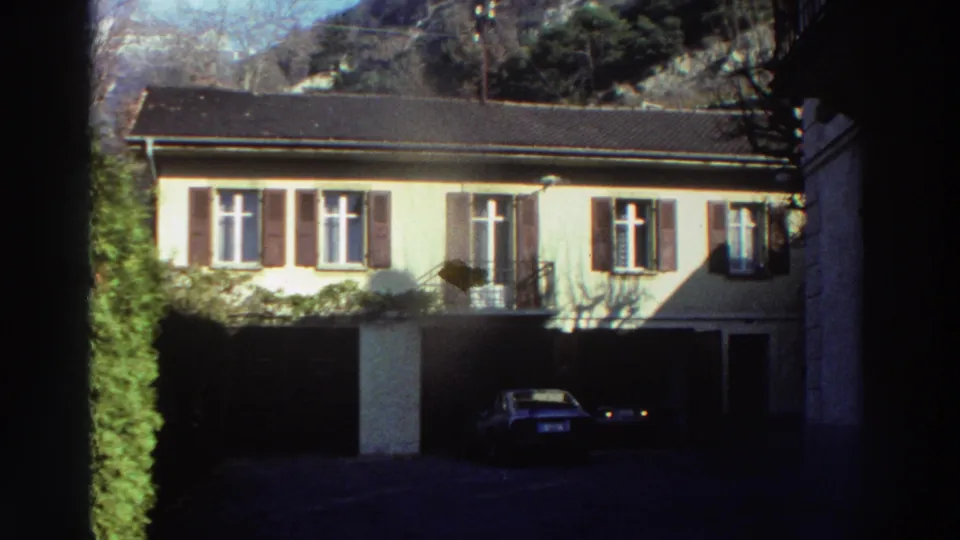 Shuttered residential building and parking area shown in 8mm home-movie footage from the supplied Greece 1976 metadata.