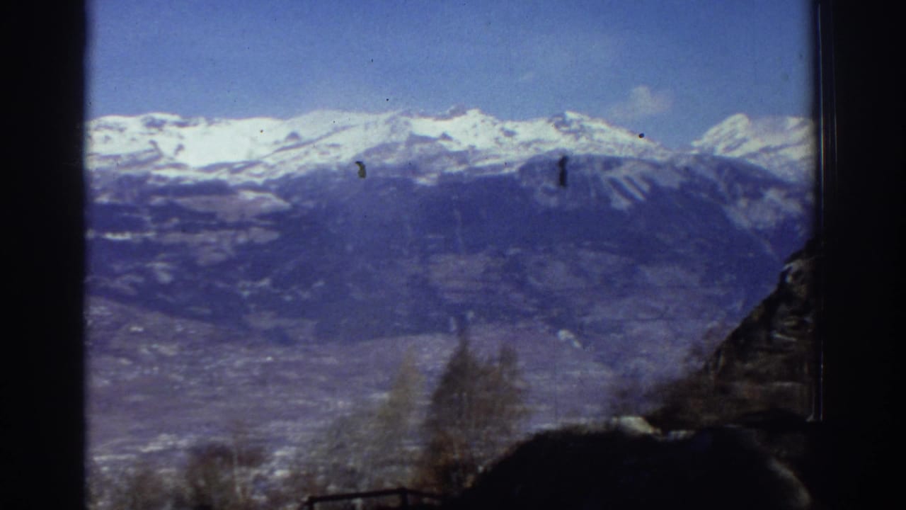 Snowy mountain range and valley with dark frame borders and hillside shadow.