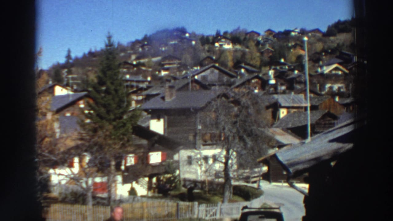 1976 Greece exterior view of hillside homes and trees, framed by dark 8mm gate edges during a slow pan.