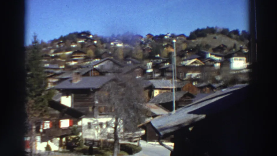 1976 Greece home-movie view of rooftops, hillside houses, trees, and a road, partly obscured by the film frame edge.