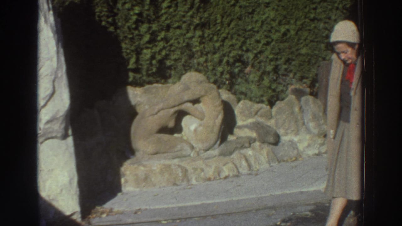 Woman looks down while standing at the edge of a stone sculpture scene.