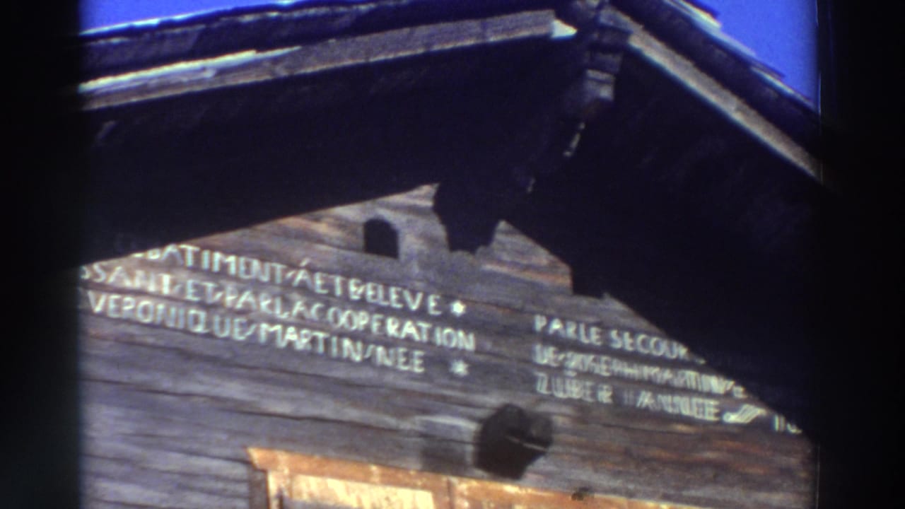 Wooden facade with more visible French inscription and heavy roof shadow.