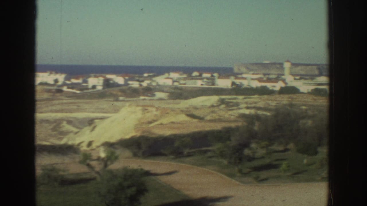 Coastal village and sandy hillside seen through dark 8mm frame borders.