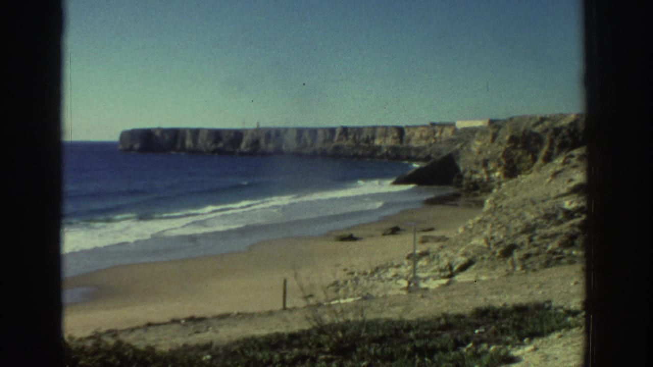 1976 Greece home-movie view of a beach, white surf, blue sea, and rocky cliffs under clear daylight.
