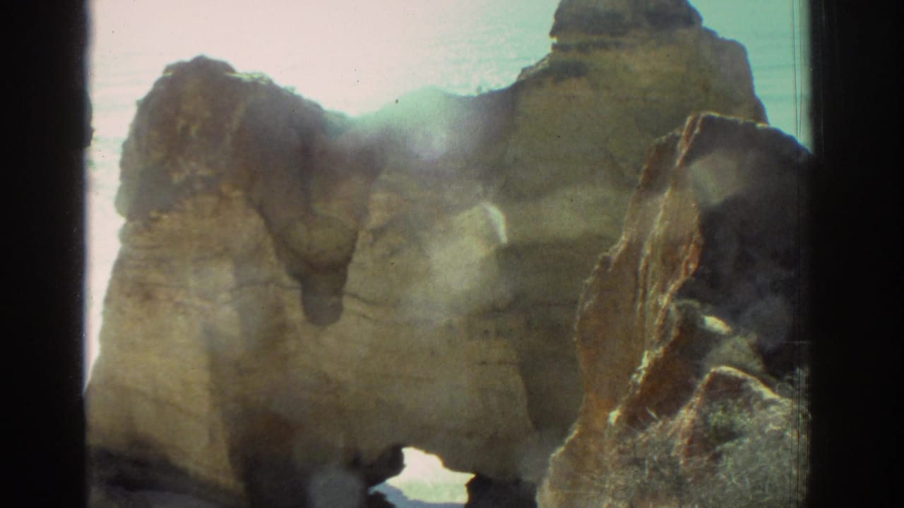 1976 Greece 8mm frame showing weathered coastal rocks and a bright opening toward the sea.