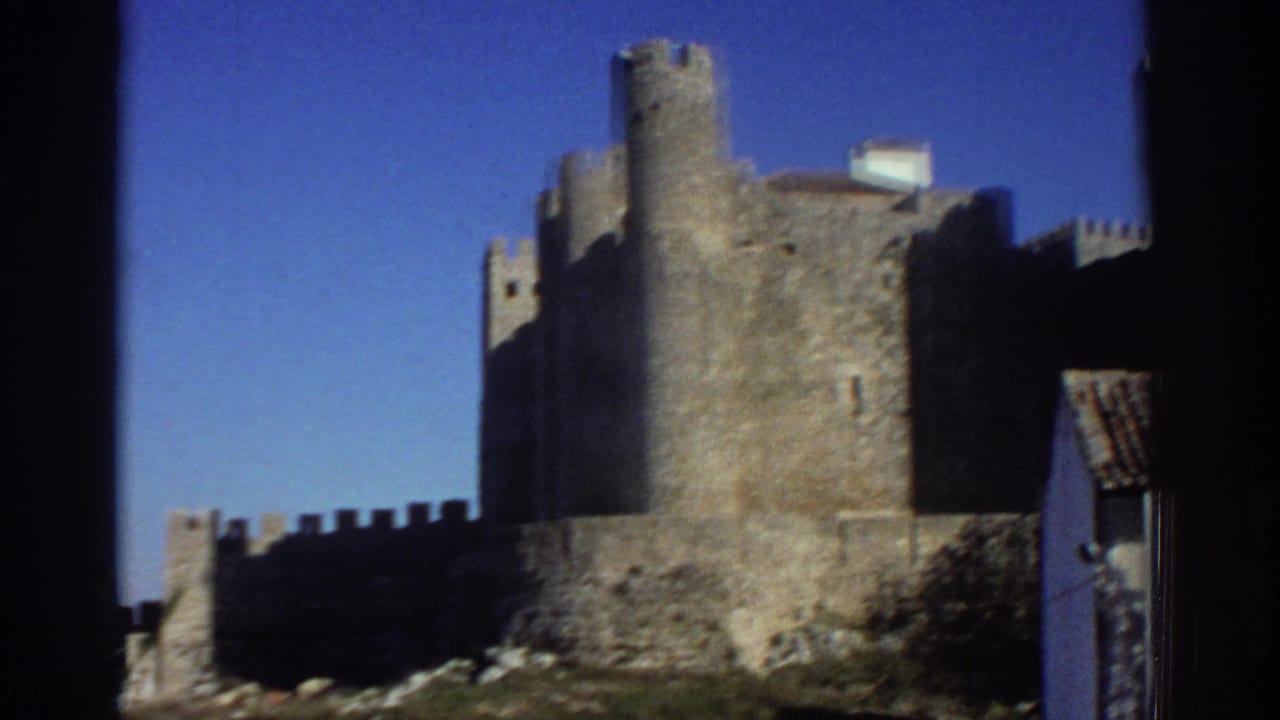 1976 Greece home-movie view of a round castle tower, stone walls, and open blue sky from a handheld angle.