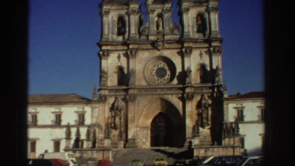 1976 Greece 8mm travel frame showing the cathedral facade with steps and several parked cars at the base.