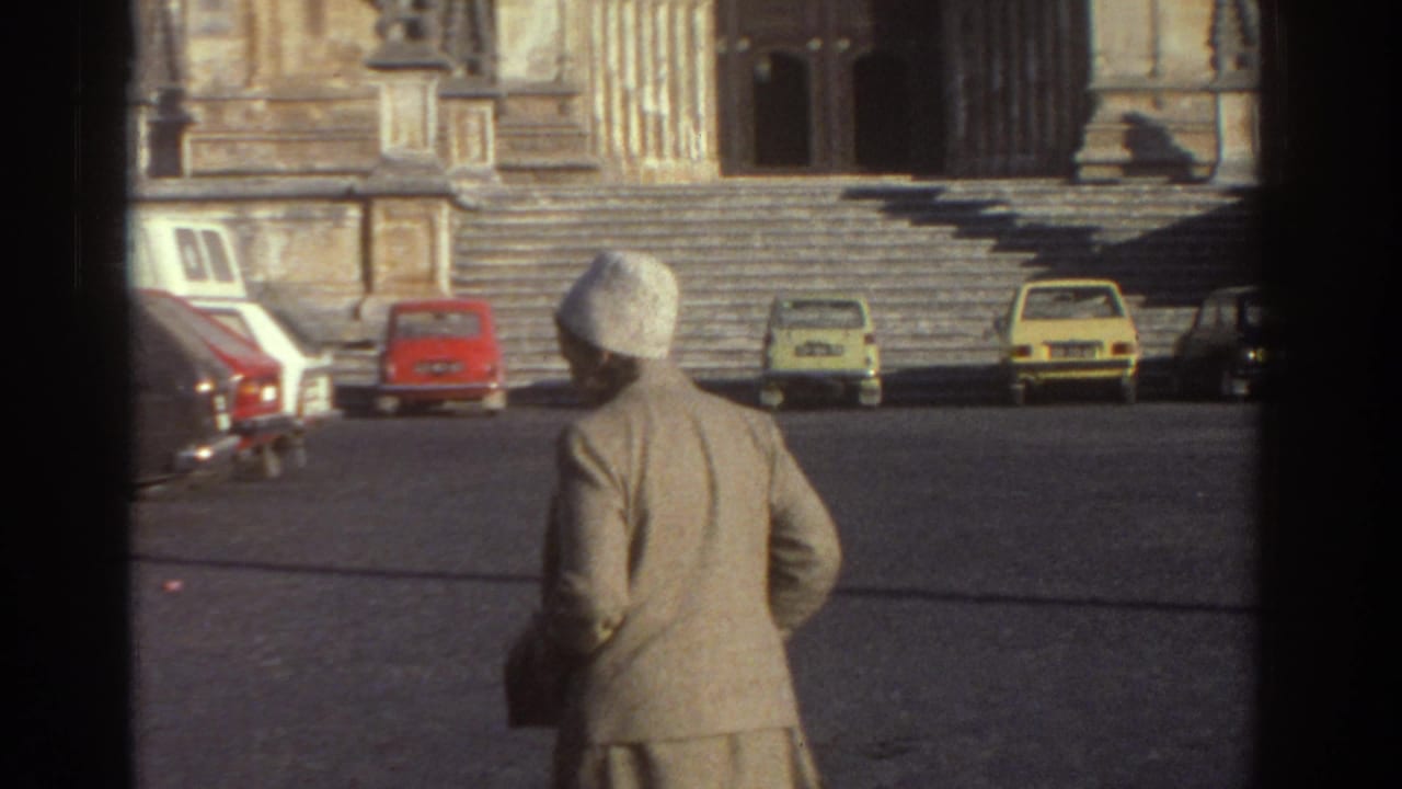 Woman in a light-colored coat and white hat crosses a Greek cathedral square toward the ornate stone entrance, with 1970s cars nearby.