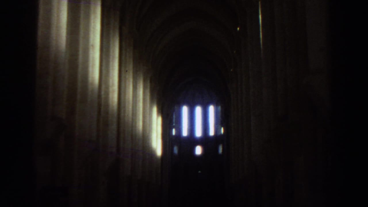 1976 Greece travel footage appears to show a dim cathedral nave with tall stone arches and glowing windows in the distance.