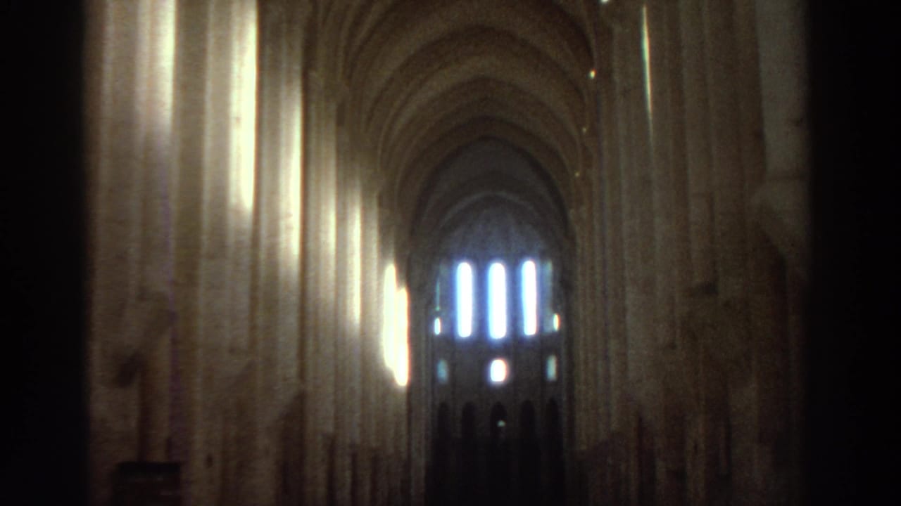 Vaulted church interior with tall columns, bright wall light, and distant arched windows.