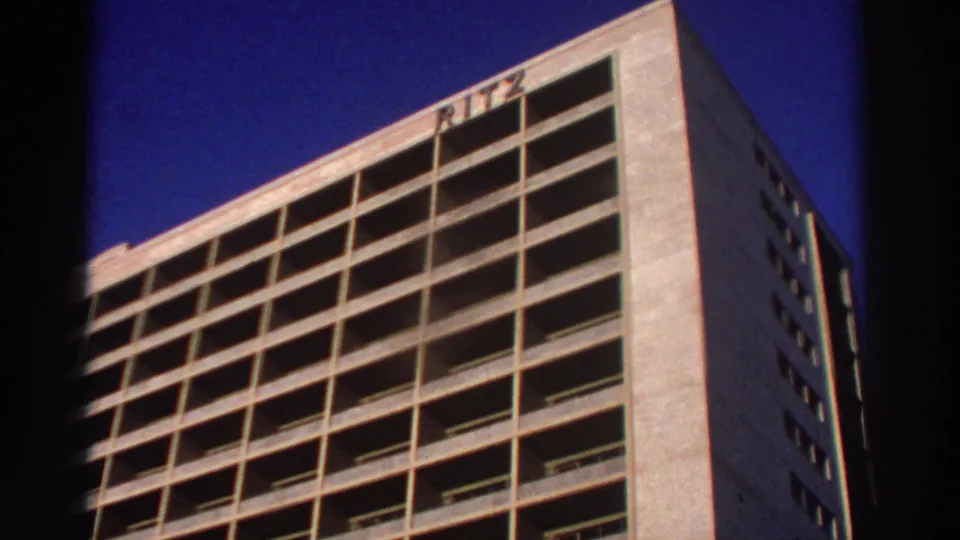 1976 Greece 8mm frame with a closer low-angle view of the RITZ hotel facade, emphasizing concrete bays and the roofline sign.