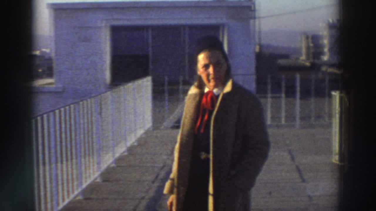 Man walking beside a white rooftop railing with a small structure behind him.