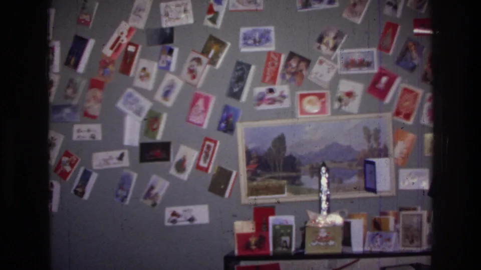 1976 Harlem home interior with a dense arrangement of holiday cards, a framed landscape picture, and small decorations on a table.