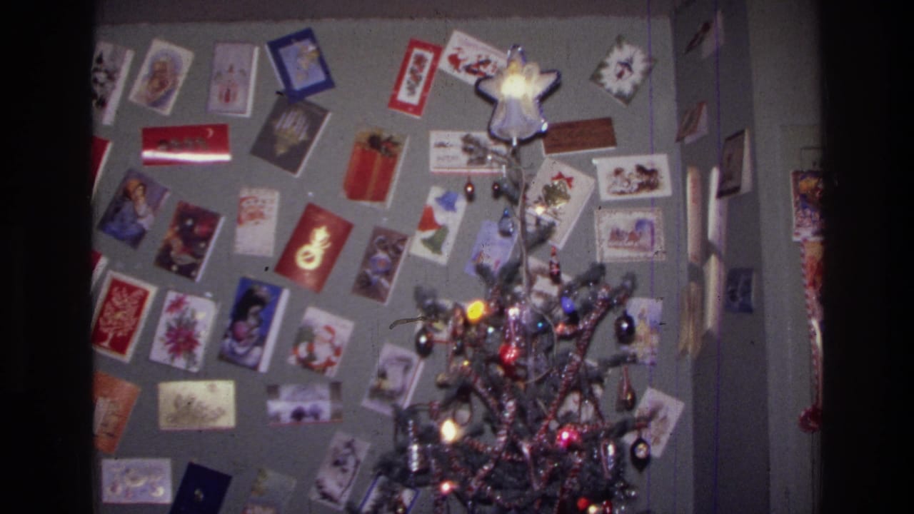 Christmas tree with ornaments and a wall of holiday cards in a private interior.