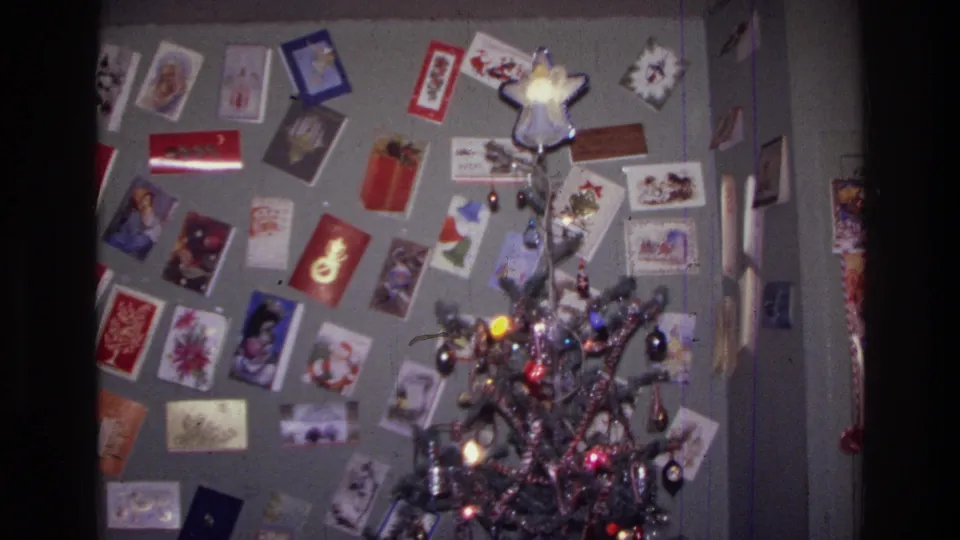 1976 Harlem interior with a decorated Christmas tree, star ornament, and many holiday cards pinned across the wall.