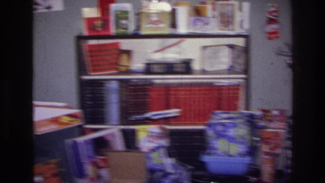 1976 Harlem interior with red-bound books, holiday cards, gift packaging, and toys near shelves during Christmas morning filming.