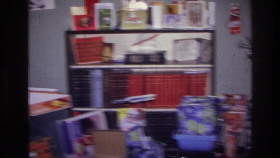 1976 Harlem interior with red-bound books, holiday cards, gift packaging, and toys near shelves during Christmas morning filming.