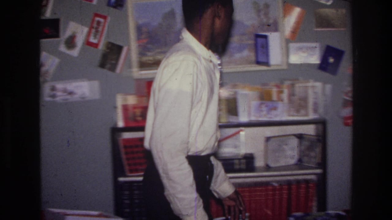 Person stands near shelves below a wall of Christmas cards and framed pictures.