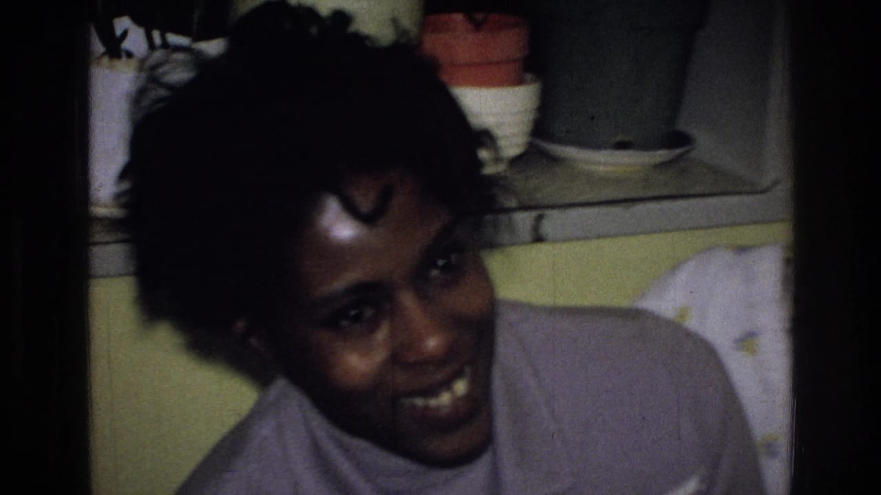 Woman smiling close to the camera in a small indoor room.