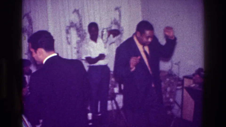 The final frame shows the suited dancer mid-motion beside guests in the purple-shifted 1976 Harlem home-movie scene.