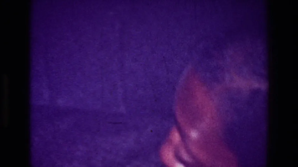 Degraded 1976 Harlem frame with heavy purple cast, a dark obscured form, and a reddish rounded shape in the lower right.