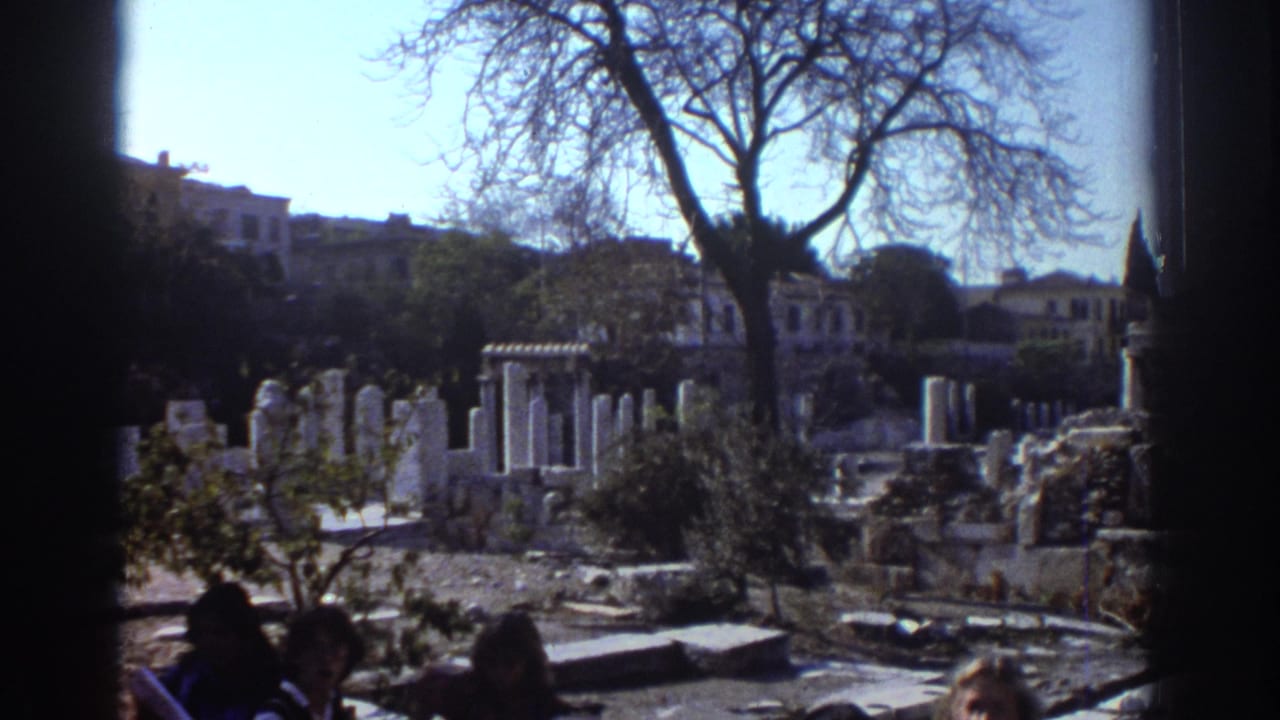 Tel Aviv home-movie frame showing sunlit stone ruins or historic structures, bare trees, and partial figures at the bottom edge.