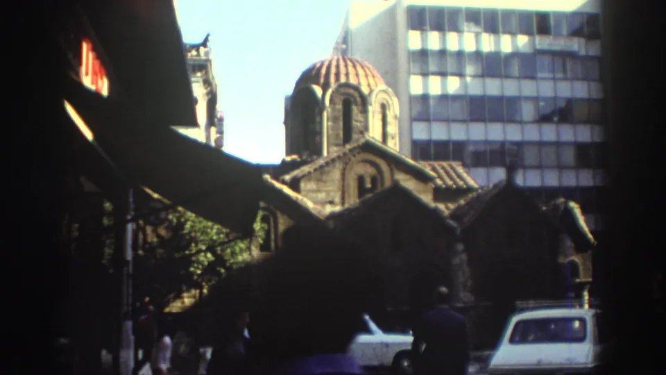 1976 Tel Aviv street view of a red-domed historic church-like building framed by dark foreground awnings and modern high-rise windows.