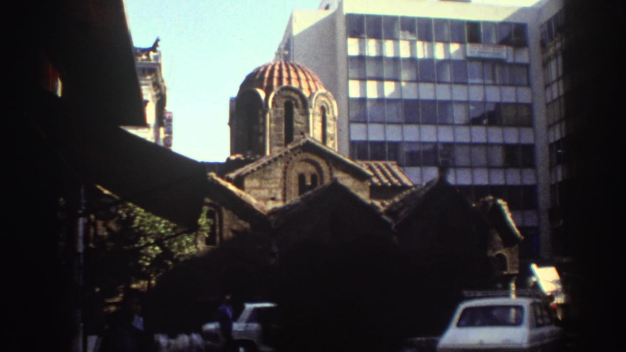 Red-domed stone church and modern building viewed from a shaded city street.