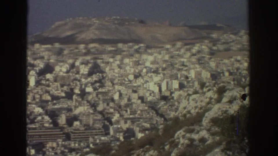 1976 Tel Aviv hilltop view showing dense pale buildings beyond rocky foreground terrain under a hazy sky.