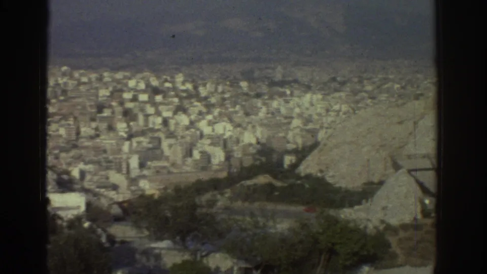 1976 Tel Aviv hilltop panorama showing dense buildings, foreground trees and a partial structure at the right edge.
