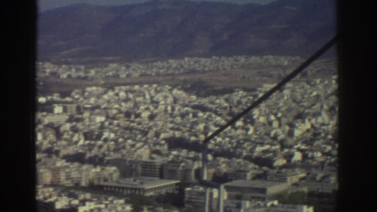 Elevated 1976 Tel Aviv city view with compact apartment blocks, distant hills, and a diagonal support beam in the foreground.