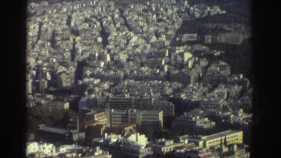1976 Tel Aviv aerial-style view showing dense mid-rise buildings, street grids, and greenery on soft 8mm film.