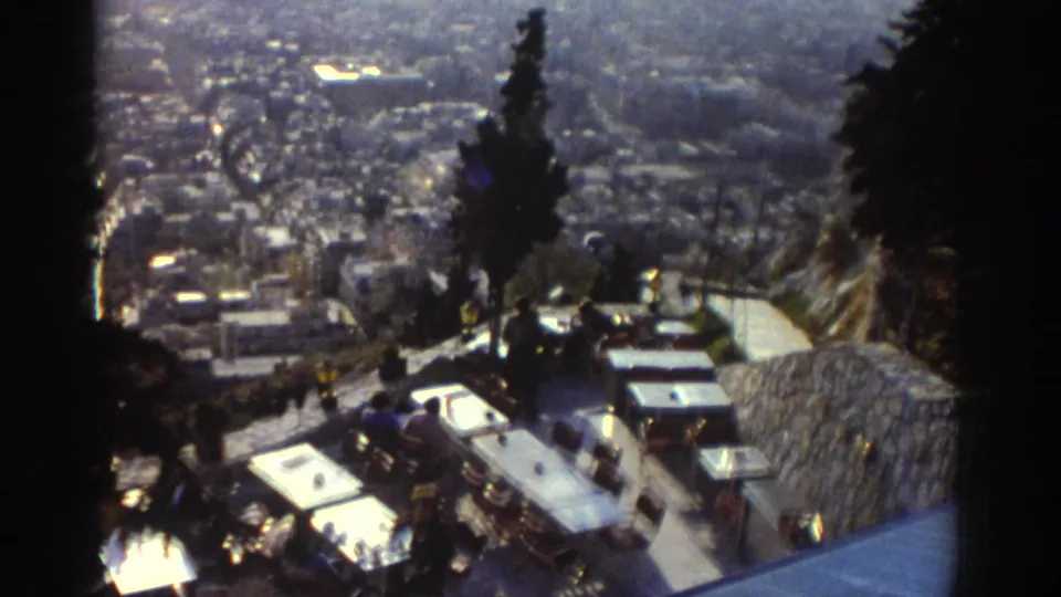 1976 Israel home-movie frame showing an outdoor terrace and parked cars above a dense city view.