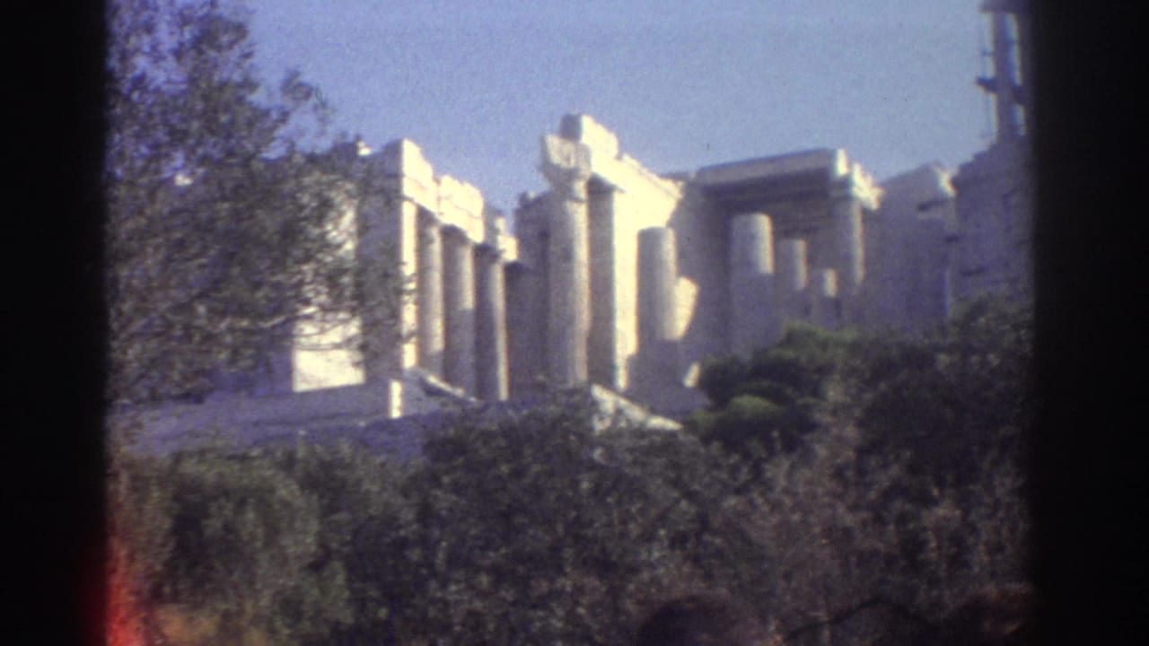 Metadata-supported 1976 travel frame showing pale classical ruins with columns, greenery and blue sky in soft 8mm color.