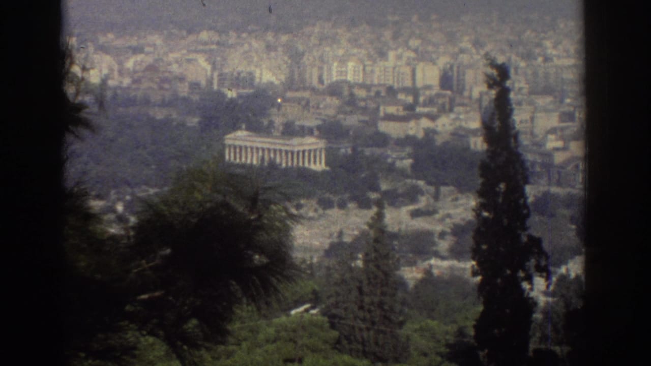 Distant columned building seen through trees above a dense cityscape.