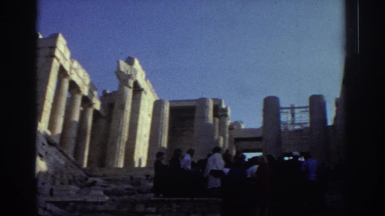 Groups of visitors move through a stone ruin with pillars and a raised walkway.