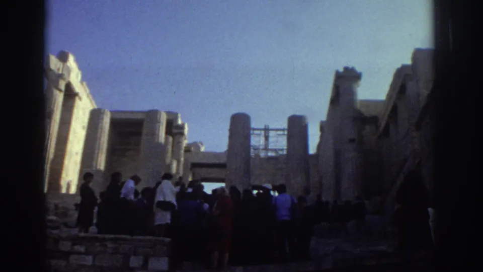 Home-movie view from 1976 Israel of tourists gathered in a stone passage with pillars, walls, and strong sunlit contrast.